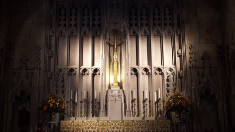 spot lighted altar with reredos, crucifix, and candles