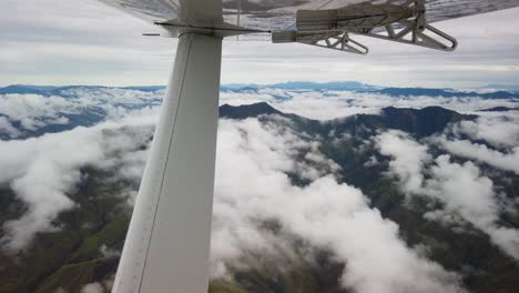 vista desde un pequeño avión volando sobre las nubes y la cordillera.