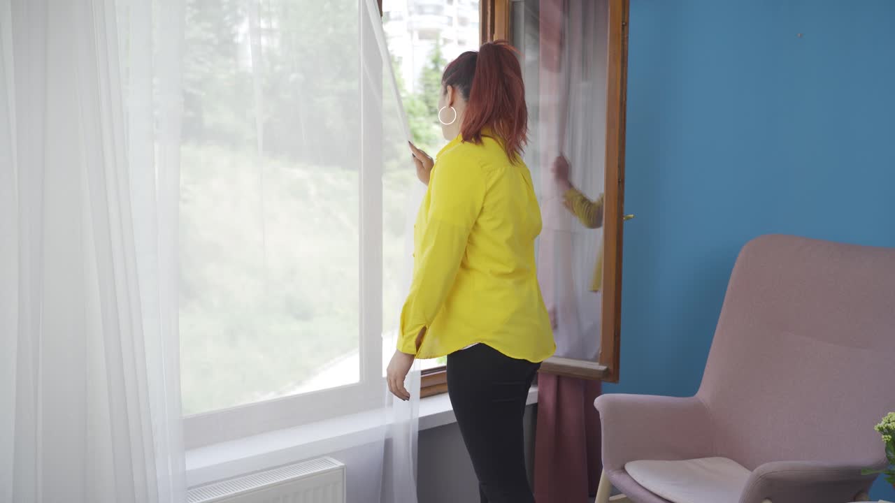 집의 커튼을 닫는 여자.