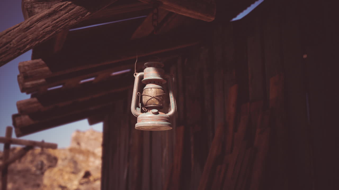 Antique lantern hanging from a wooden porch in a rustic desert cabin