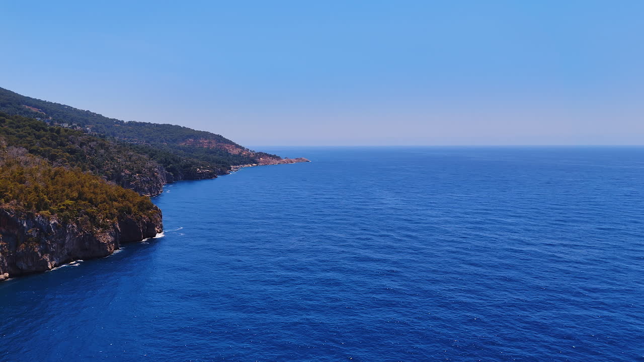 Clear blue ocean and cliffs. Stunning blue ocean stretches to horizon, meeting rugged cliffs under clear sky on a sunny day