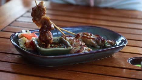 hand serving grilled skewers from a plate