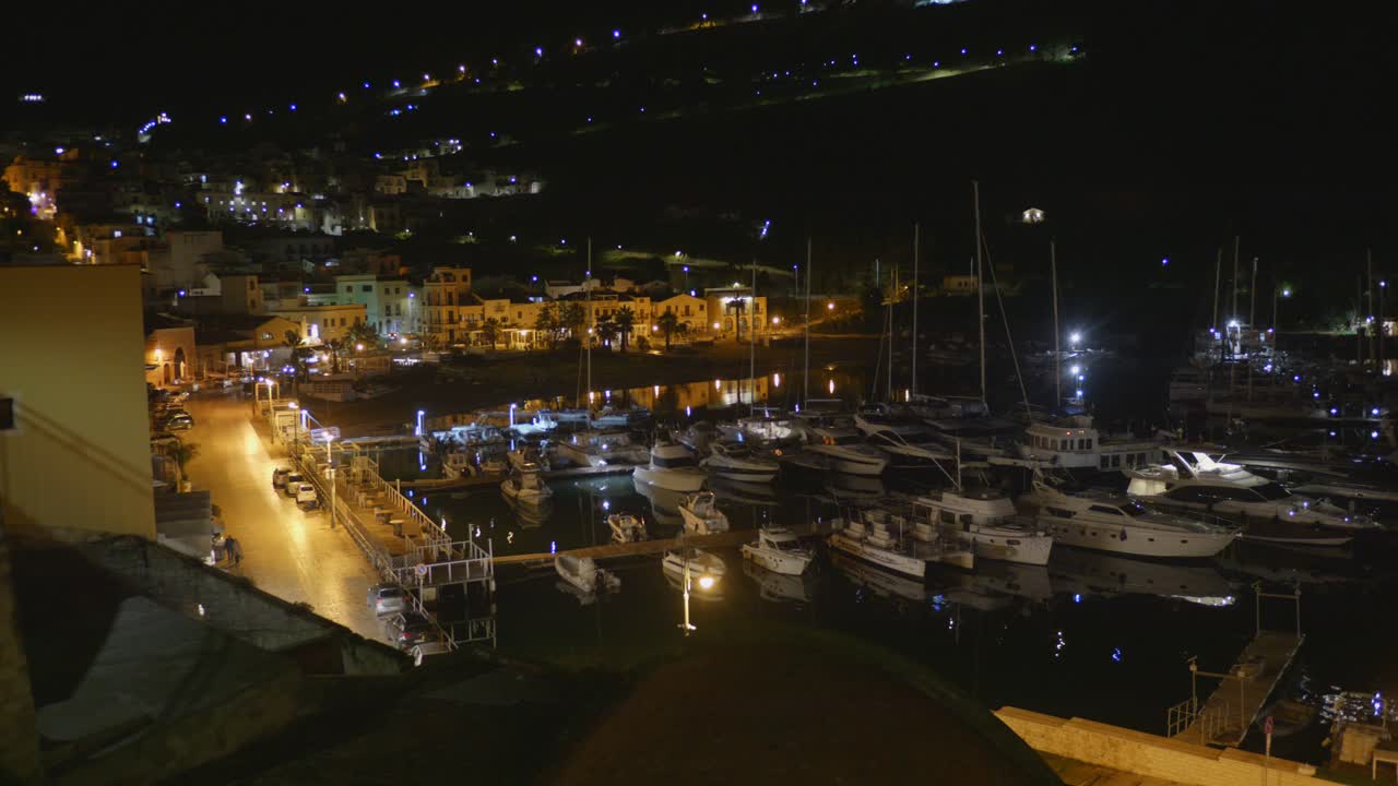 Nighttime view of Castellammare del Golfo Harbour, Sicily, Italy with lights reflecting on water