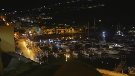 nighttime view of castellammare del golfo harbour, sicily, italy with lights reflecting on water