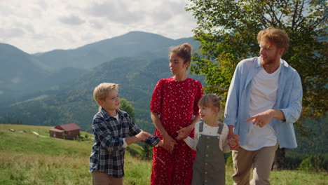 family enjoying travel nature walking on mountain hill. parents rest with kids.