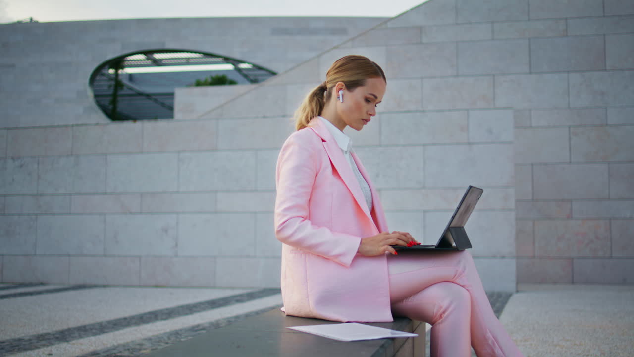 hermosa mujer independiente escribiendo correo electrónico en la computadora portátil sentada en el banco de la calle moderna.