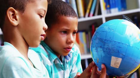 escolares mirando el globo en la biblioteca de la escuela