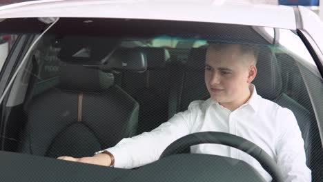 young stylish man in a prestigious luxury car at a car dealership. auto business, car sale