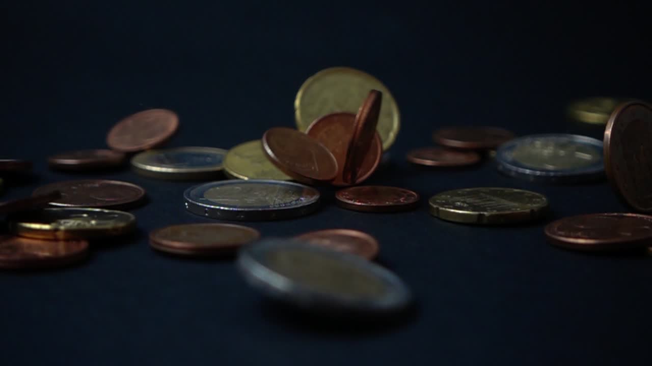 Coins fall on a black background. Slow motion