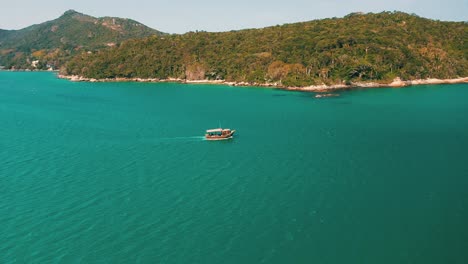 vista aérea de un barco turístico de madera en un hermoso mar turquesa y un paisaje tropical paradisíaco