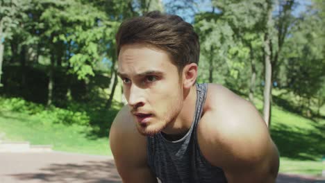 portrait of tired runner man breathing after run marathon in city park