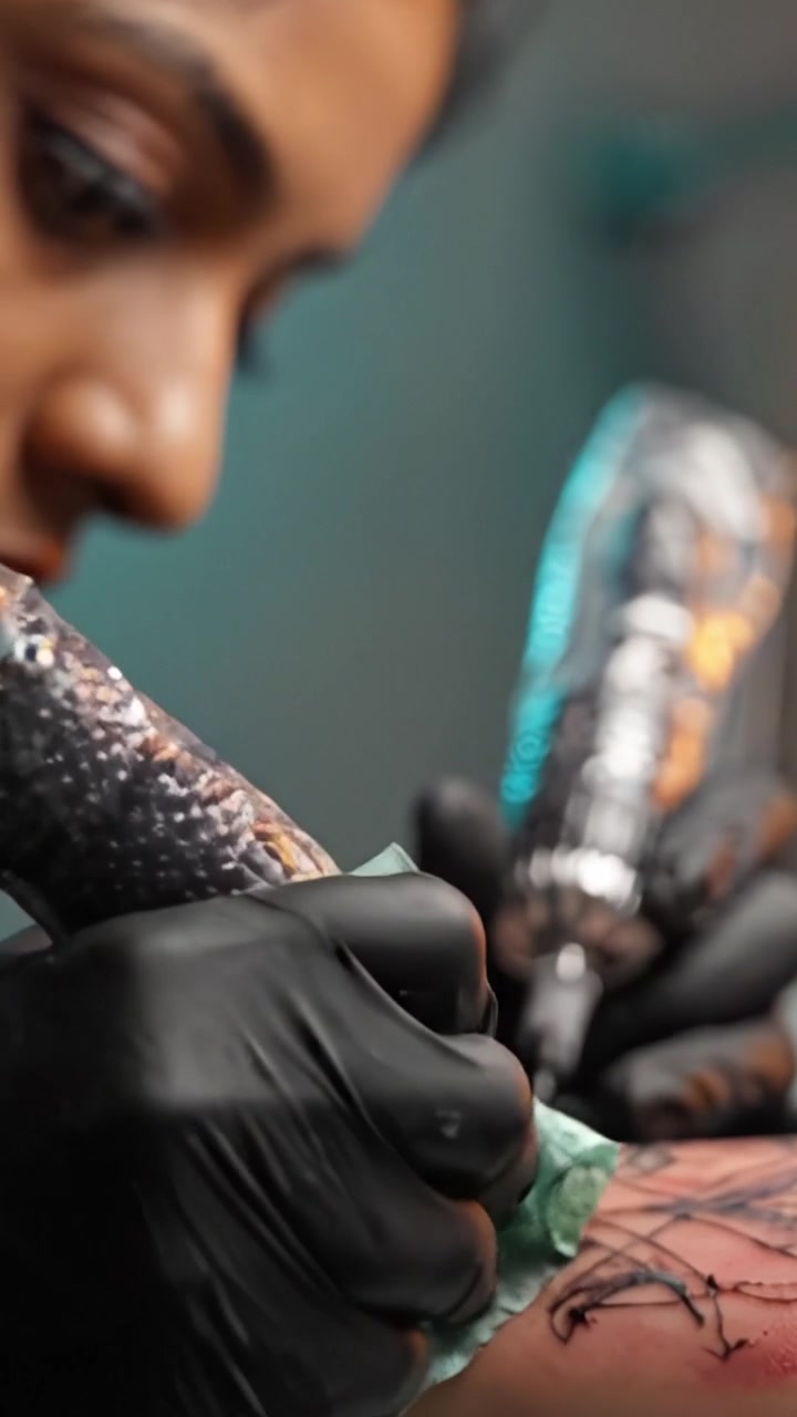 Un Primer Plano de un Hábil Tatuador Creando Diseños Intrincados en la Piel con Precisión y Cuidado, Destacando el Arte y la Técnica de la Tinta Corporal.