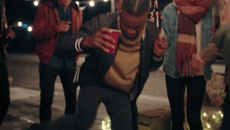 young-man-dancing-multi-ethnic-group-of-friends-having-fun-on-rooftop-at-night-enjoying-celebration-party