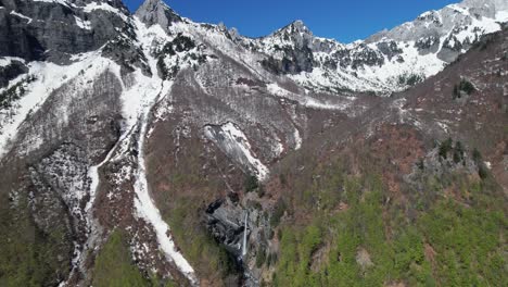 cascada escondida en la ladera de la montaña con picos altos cubiertos de nieve