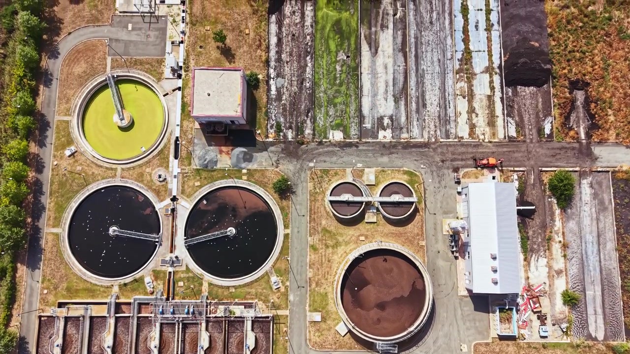 View of a water treatment facility with tanks, buildings, and roads during daytime