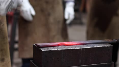 blacksmiths forging hot metal with hammer in workshop