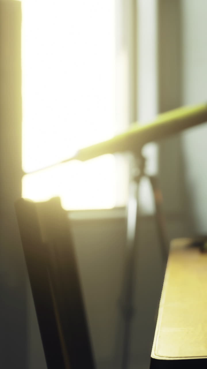 Sunlight shines through window onto desk and chair with telescope nearby