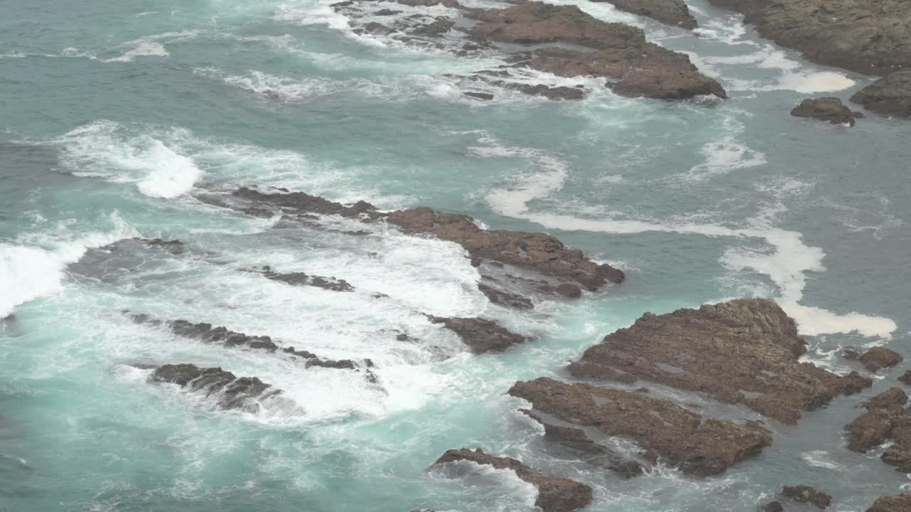Gros plan sur des vagues marines s'écrasant contre des rochers par une journée brumeuse et nuageuse