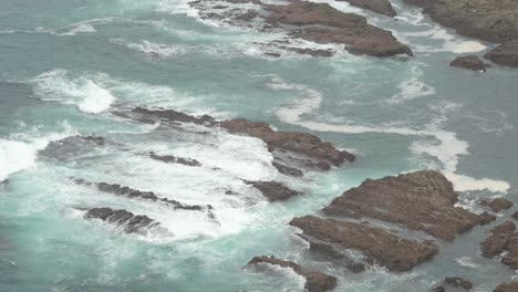 close-up of sea waves crashing against rocks on a foggy and cloudy day