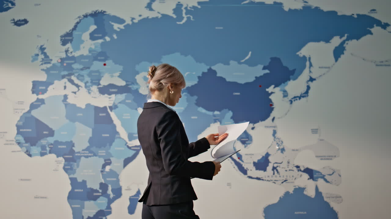 Businesswoman analyzing global economy watching estimating world map back view
