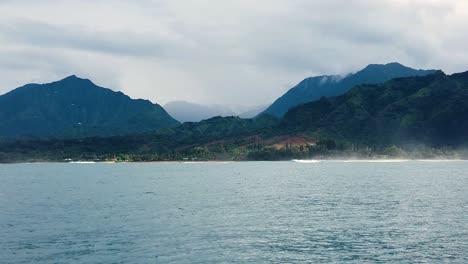 hd 120fps hawaii kauai boating on the ocean floating right to left with mountain and green hills in distance with boat spray in foreground