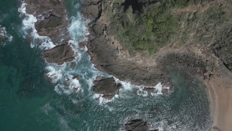 straight down aerial flyover, rugged ocean cliff and shore rocks