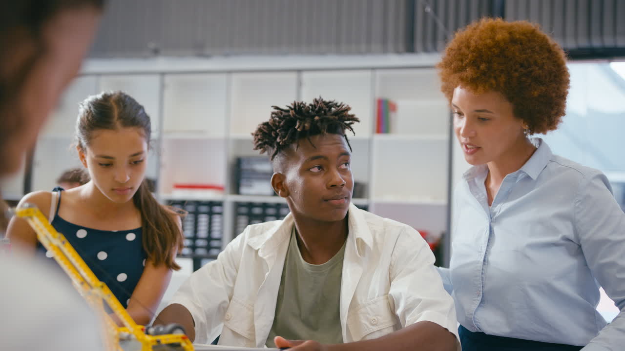 Female Teacher With High School Students Using Digital Tablet In STEM Class