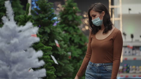 Una-Mujer-Con-Una-Máscara-Protectora-En-Una-Joyería-Y-Guirnaldas-Con-Juguetes-Para-árboles-De-Navidad-Y-En-Casa.-Guirnaldas-Navideñas-Y-Decoración