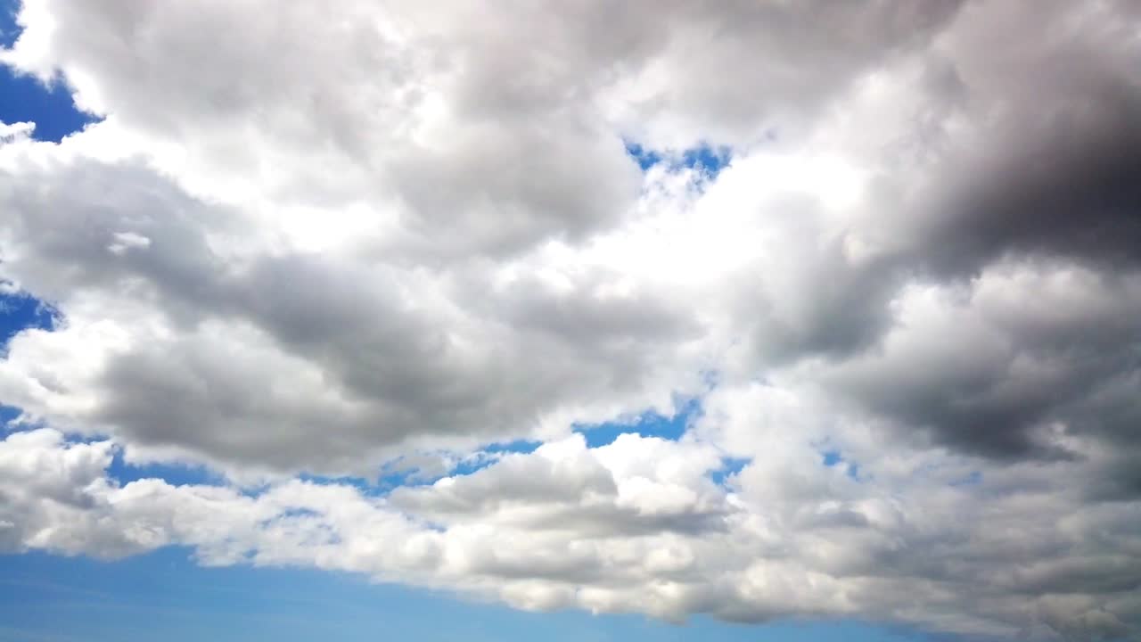 Think dark cloud timeplapse with bright sunlight peeking behind the cloud with blue sky in the background