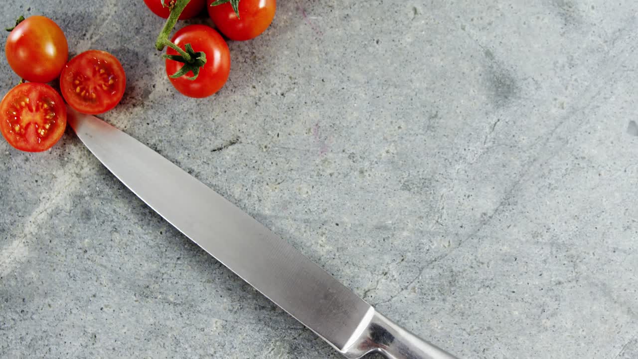 tomates de cereza y cuchillo de cocina en concreto