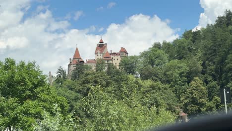bran castle in the forest seen from a car rearview mirror
