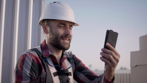 construction worker using smartphone on rooftop