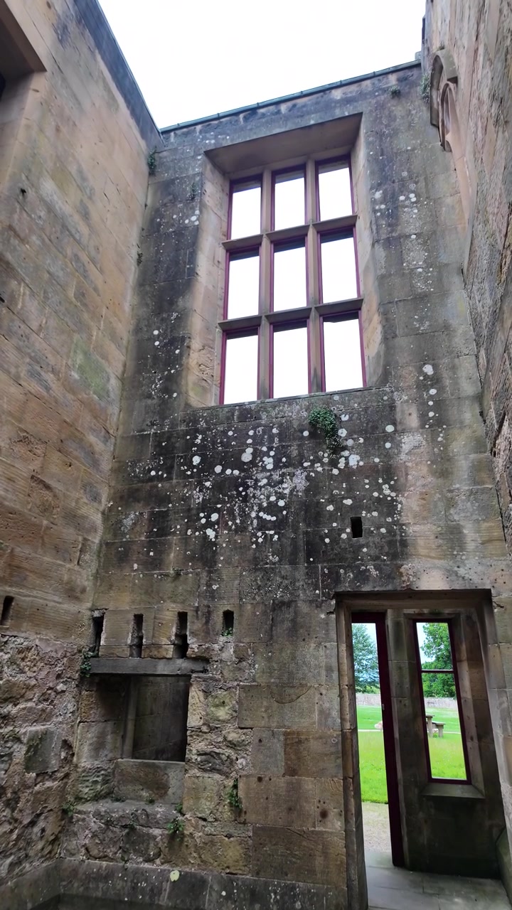 Muros de piedra, ventana con parteluz y entrada dentro de las ruinas de un castillo inglés medieval. Video vertical.