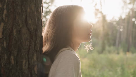 lady rests with blade of grass in mouth at sunset. young woman thinks about personal life challenges standing in forest in evening. finding peace of mind alone