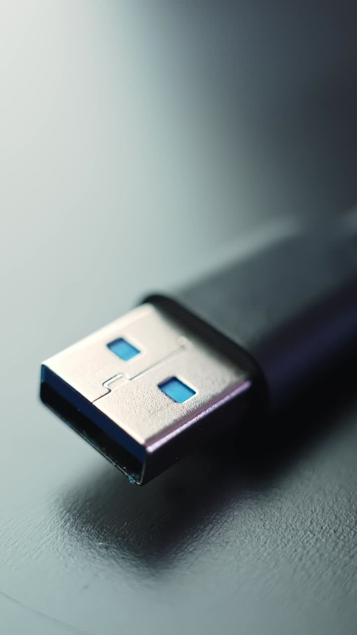 Vertical macro close-up of a USB-A plug on a gray desk with soft reflections and copy space, cool tones and calm minimal tech vibe, sharp metal detail and smooth shadow