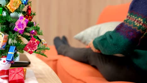 mujer sentada en el sofá usando la tableta en casa. niña enviando mensajes de texto en el touchpad durante la navidad. vacaciones de navidad celebraciones de año nuevo felicitaciones de la temporada