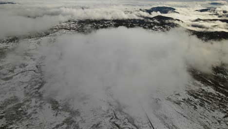 Zooming-out-drone-footage-of-a-mountain-road-disappearing-in-the-clouds