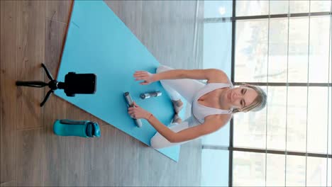coach girl in white sportswear leads video on smartphone at home coach girl in white sportswear leads video on smartphone at home a fitness trainer instructor conducts online training at home
