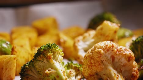 a close up macro view of fresh broccoli and cauliflower covered in seasoning on a baking tray, the vegetables cooling after roasting in an oven and part of a healthy balanced meal