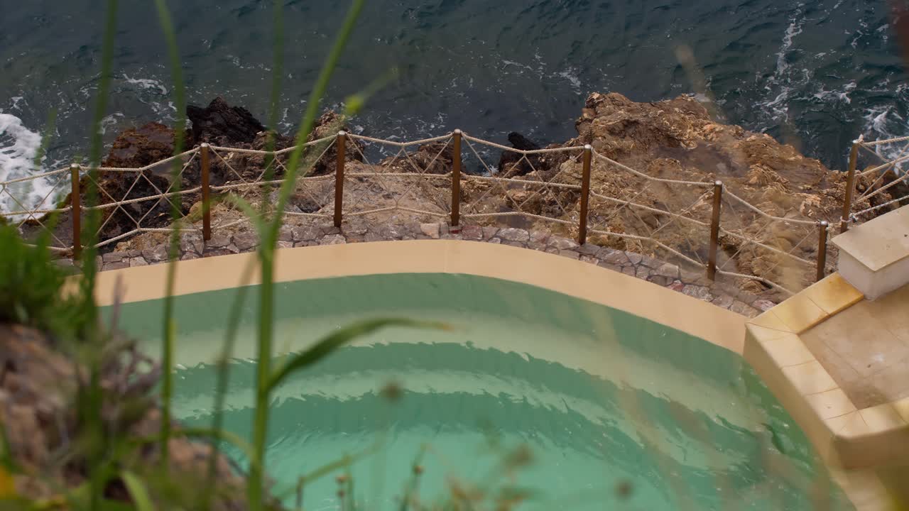 Piscine limpide près d'une côte rocheuse avec des vagues à Taormine, Sicile, Italie