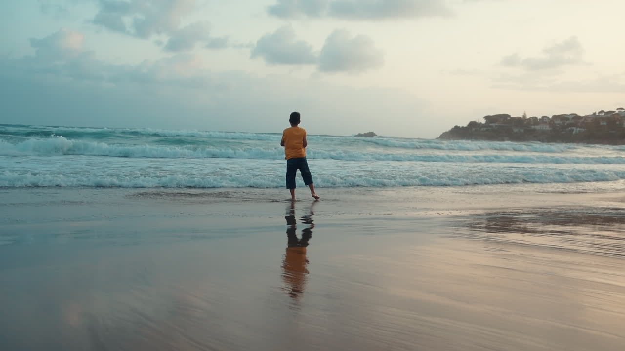 un chico feliz disfrutando de las vacaciones en la orilla del mar. un chico alegre bailando en la playa de arena.