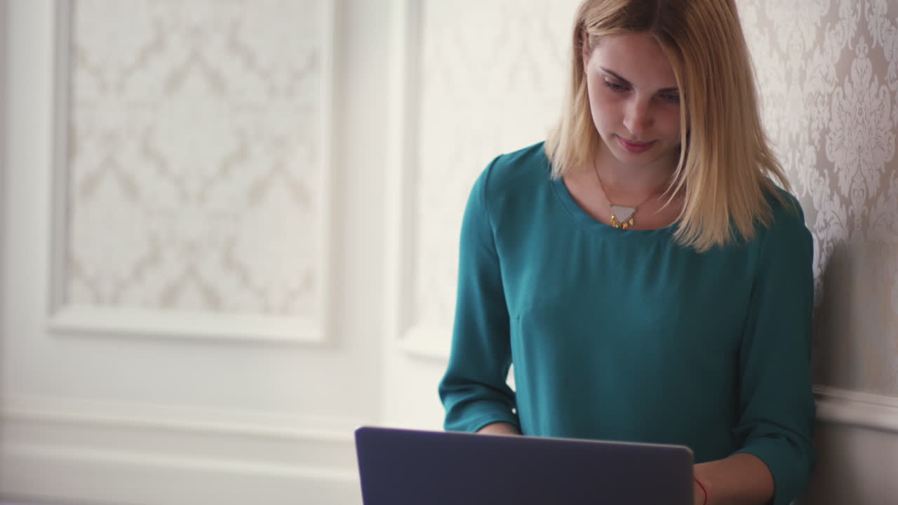 Young woman opening laptop computer for browsing internet in room interior