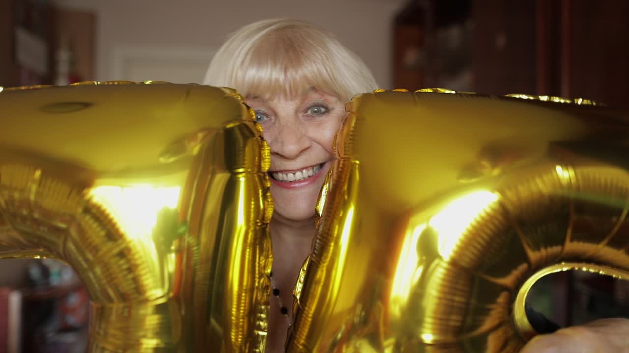 Nonna carina festeggia il suo compleanno. Tiene dei palloncini in mano