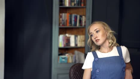 young woman sitting in a room with bookshelves