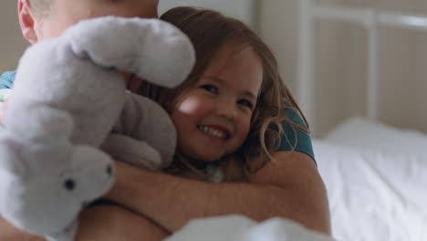 happy father hugging daughter in bed little girl laughing enjoying hug from dad loving parent embracing child having fun weekend morning at home