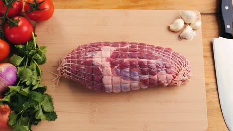 raw boneless pork roast on cutting board with vegetables