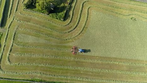 drone ascends overhead in birdseye revealing epic fields that farmer is working in his blue tractor, aerial