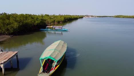 Luftdrohnenaufnahme-über-Dem-Fluss-Kartong-In-Gambia-Mit-Blick-Auf-Ein-Schwimmendes-Boot-Und-Die-Wunderschöne-Landschaft-Mit-Bäumen-Und-Natur-An-Einem-Sonnigen-Tag