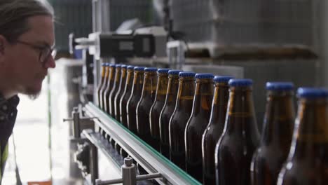 Caucasian-man-checking-bottles-of-beer-at-a-microbrewery