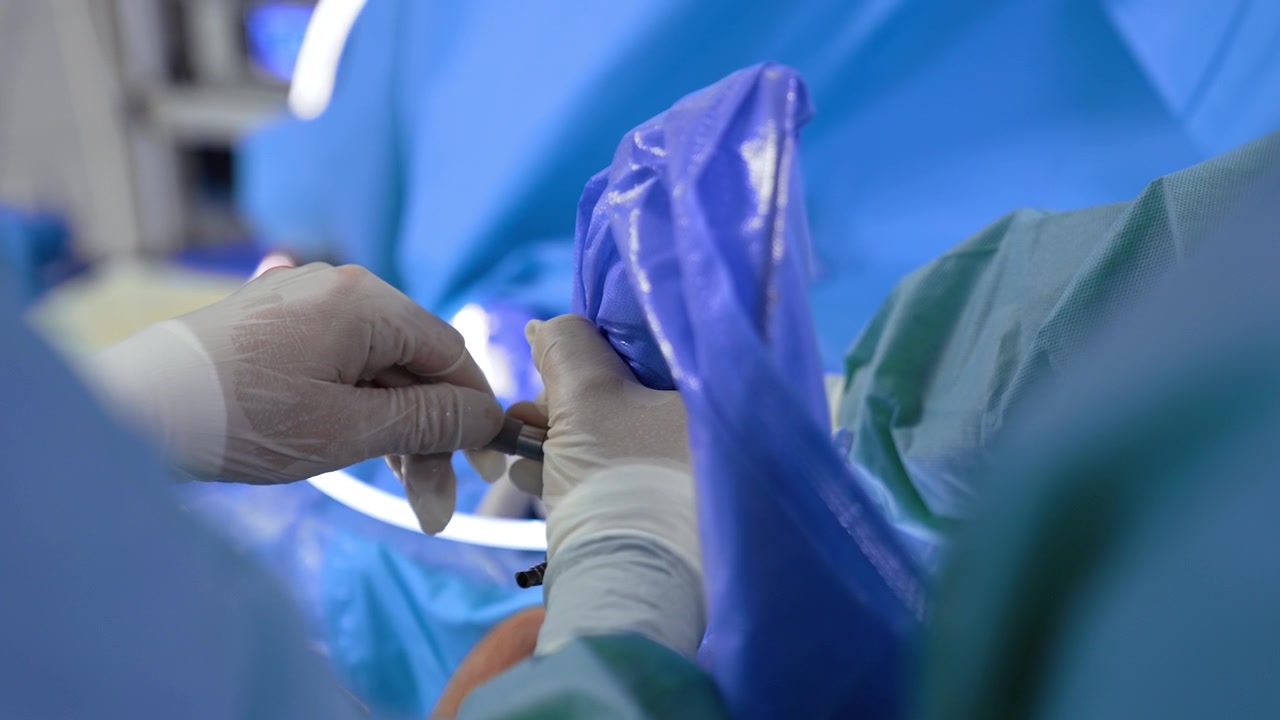 Mano di un medico con guanto in lattice che tiene uno strumento chirurgico. Il chirurgo esegue un intervento chirurgico per trauma. Primo piano. Sfondo sfocato.